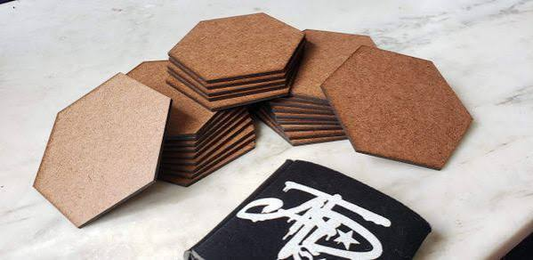 Stacks of blank hexagonal MDF coasters on a light work surface